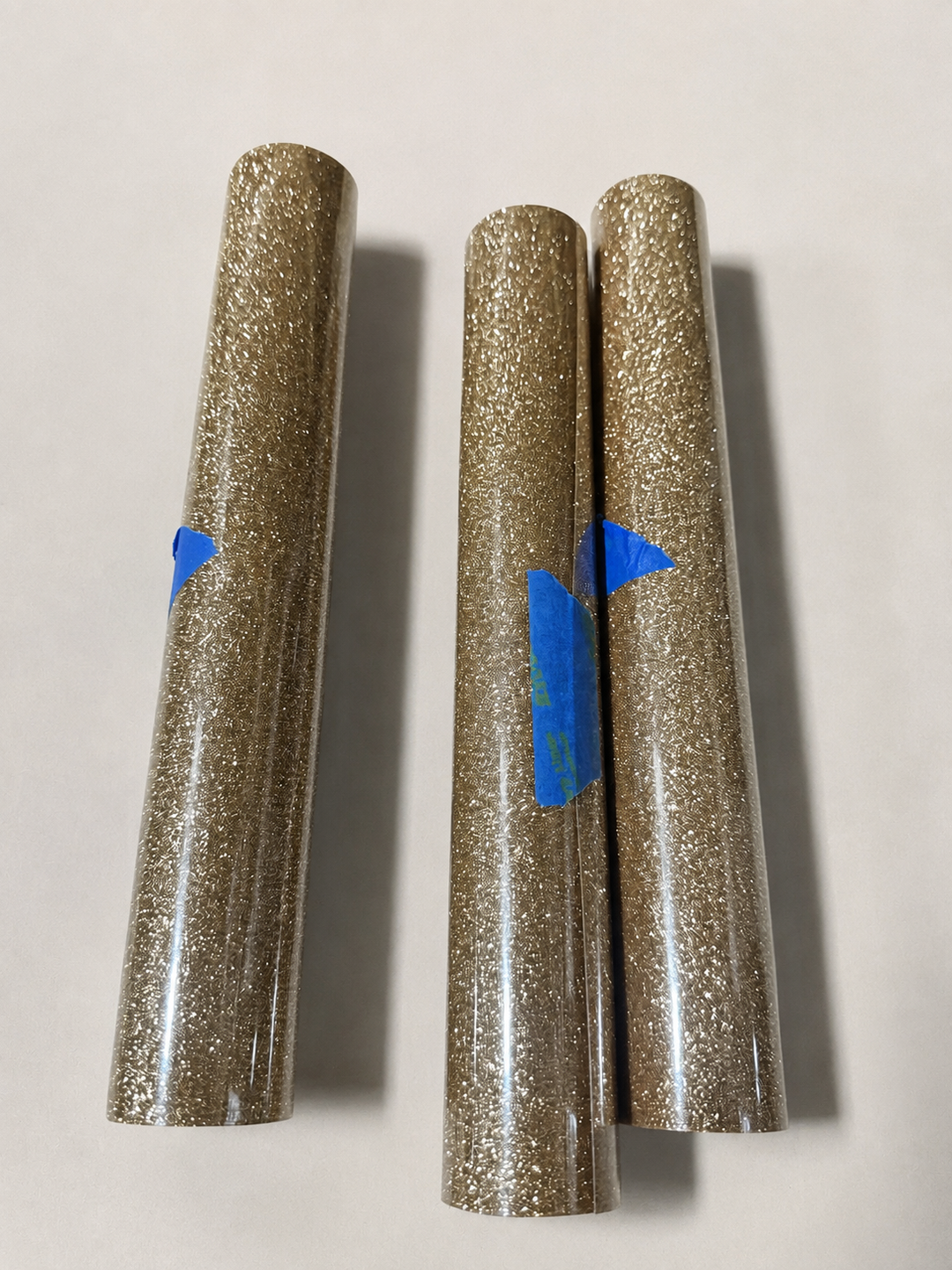Three rolls of Siser Glitter heat transfer vinyl in a champagne gold shade