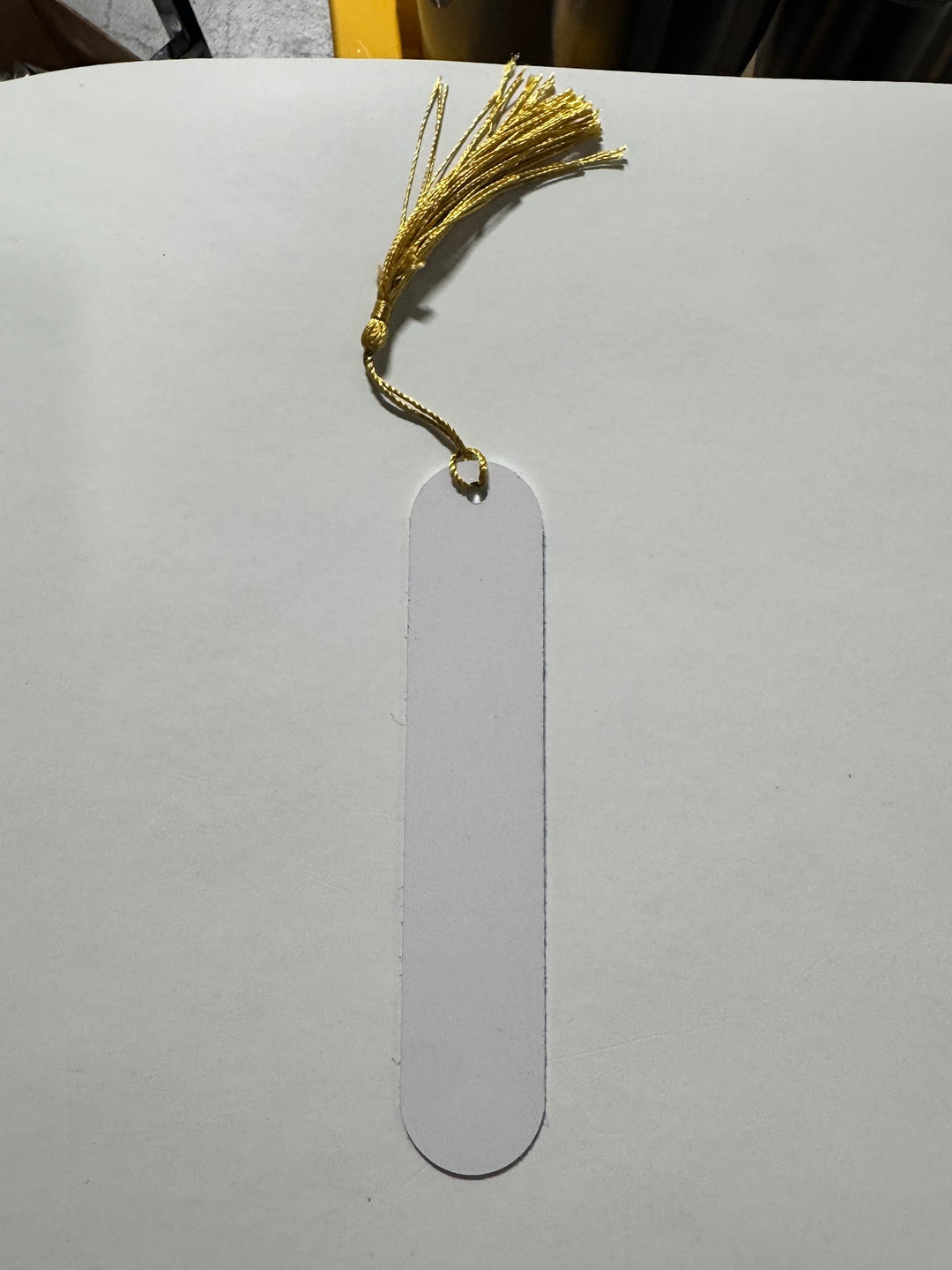 Blank white sublimation bookmark with a rounded end and a gold tassel