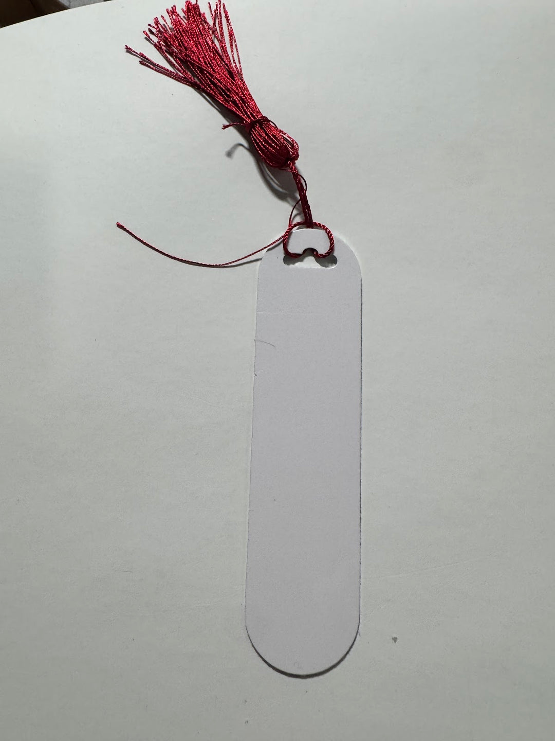 Blank white sublimation bookmark with a rounded end and a red tassel