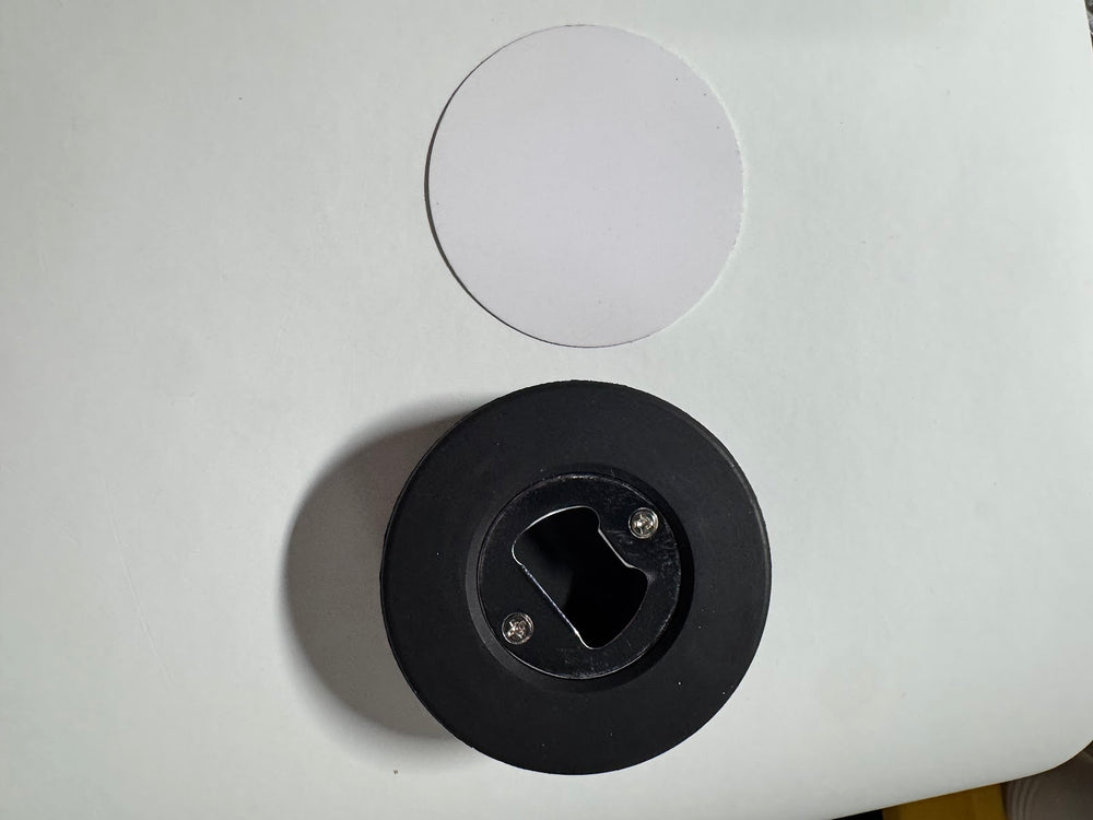Underside of the round coaster showing the recessed metal bottle opener plate