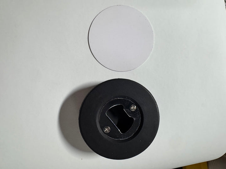 Underside of the round coaster showing the recessed metal bottle opener plate