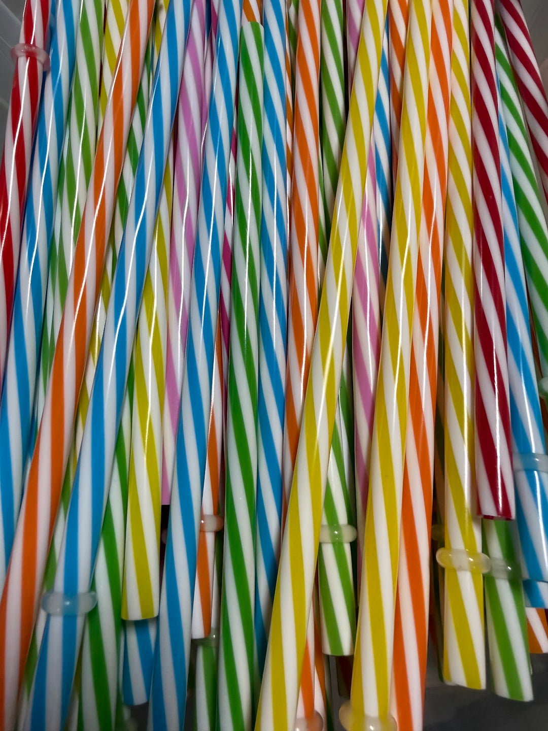 Bundle of reusable candy-stripe plastic straws in assorted colours
