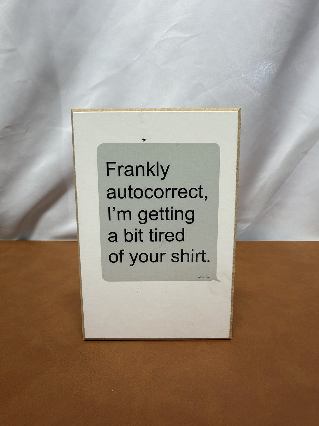 Wood sign styled like a text bubble joking about autocorrect