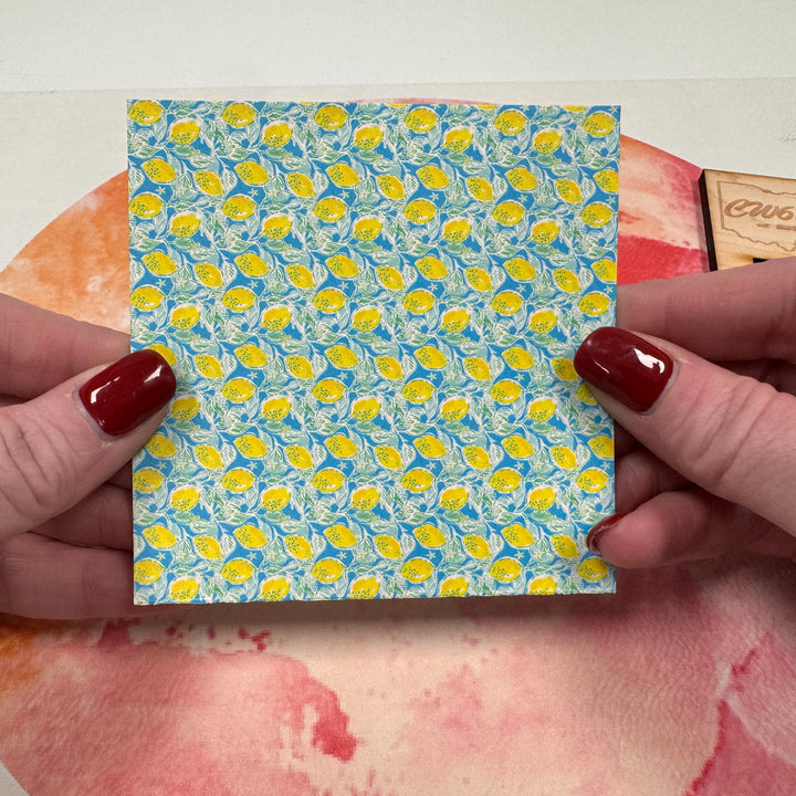 A close-up of a held pattern acrylic card with a lemon pattern