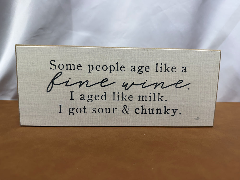 Wood sign joking about aging like milk instead of wine