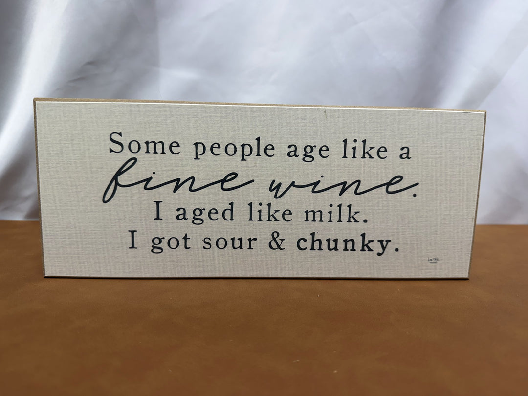 Wood sign joking about aging like milk instead of wine