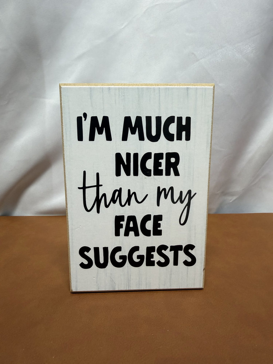 Wood sign reading I'm much nicer than my face suggests