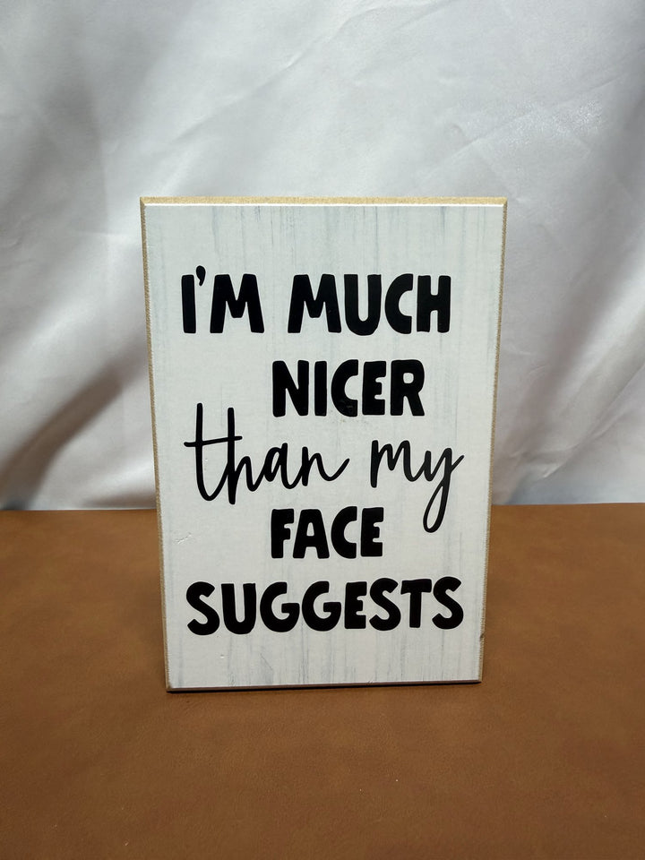 Wood sign reading I'm much nicer than my face suggests
