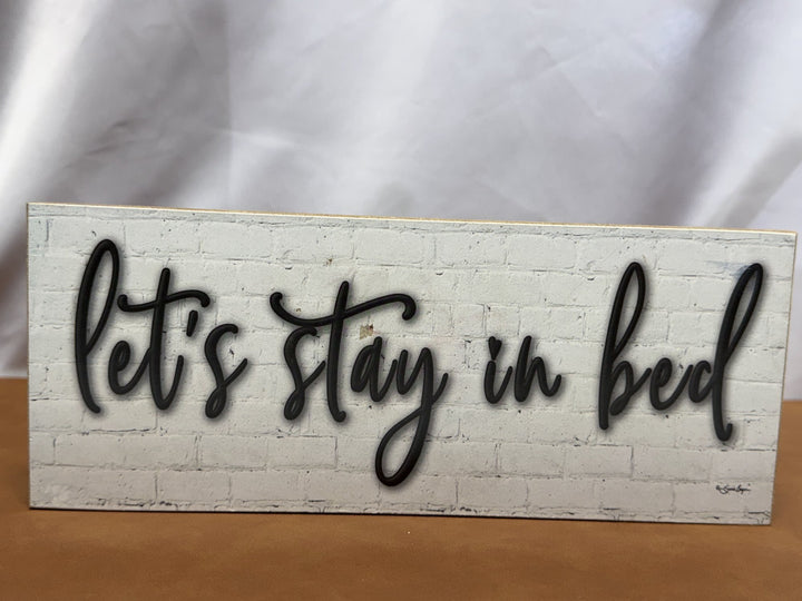 Wood sign reading Let's Stay in Bed