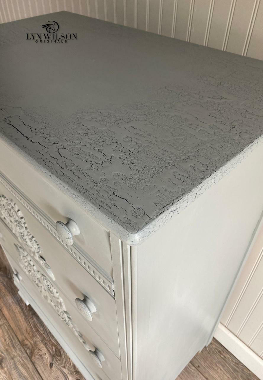Closeup of a white dresser with a gray crackle finish top