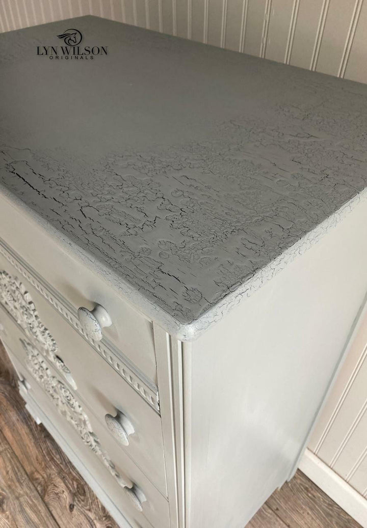 Closeup of a white dresser with a gray crackle finish top