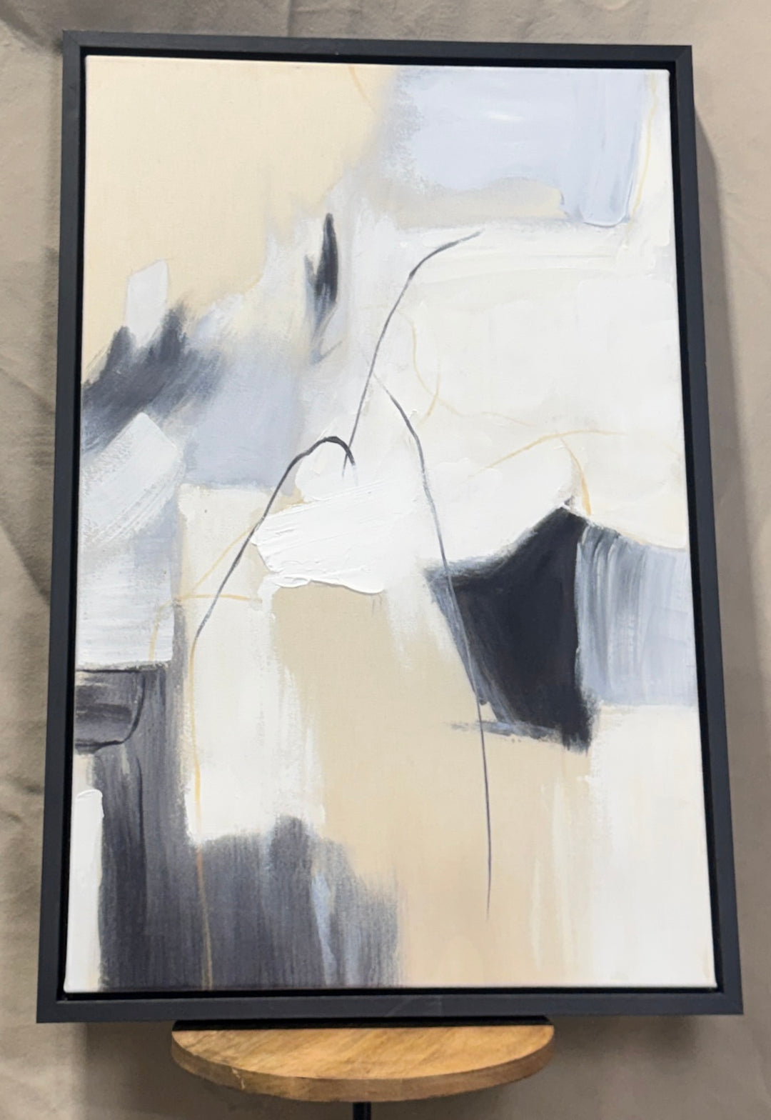 Cream, beige, gray and black vertical abstract wall art in a black frame