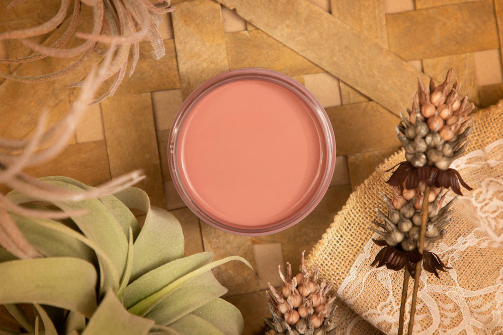 Open jar of Desert Rose Silk paint styled with dried leaves and flowers on a wicker mat