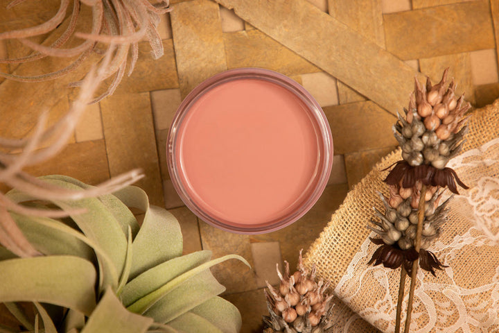 Open jar of Desert Rose Silk paint styled with dried leaves and flowers on a wicker mat