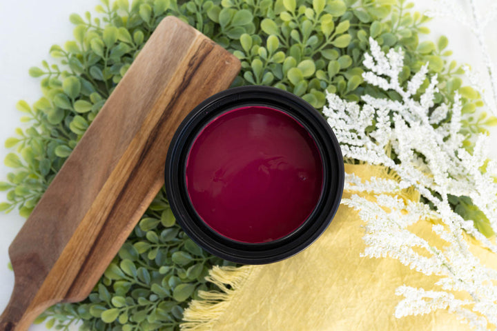Open container of Bougainvillea Terra Clay Paint styled with greenery and a yellow linen