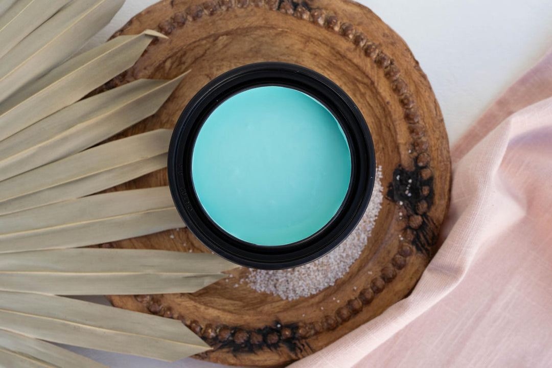 Open container of Lani's Lagoon Terra Clay Paint on a wooden board with a fan leaf