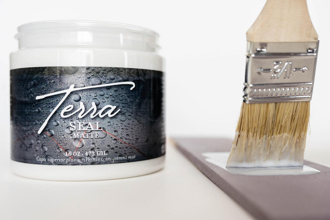 Open jar of Terra Seal next to a brush applying the sealer to a piece of wood